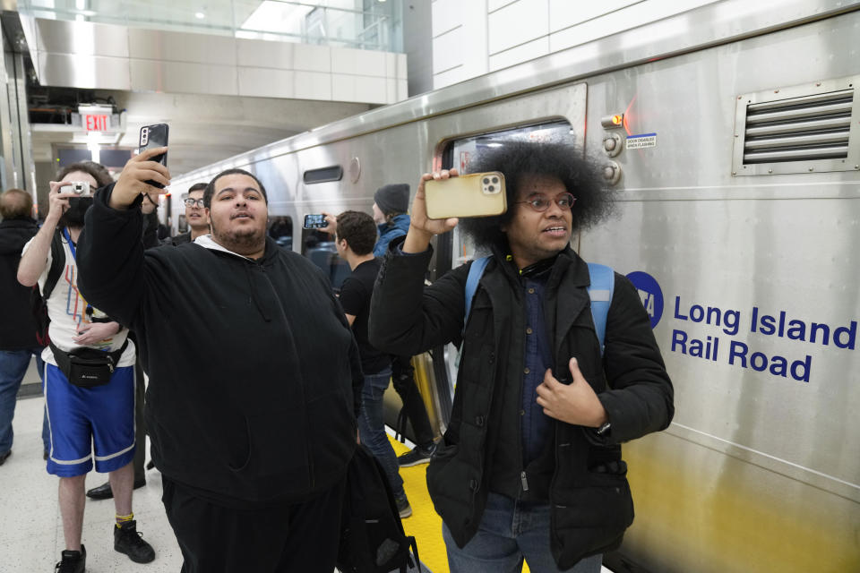 Riders take photos and videos as they exit the first Long Island Railroad train to arrive in Grand Central Station in New York, Wednesday, Jan. 25, 2023. After years of delays and massive cost overruns, one of the world's most expensive railway projects on Wednesday began shuttling its first passengers between Long Island to a new annex to New York City's iconic Grand Central Terminal. (AP Photo/Seth Wenig)