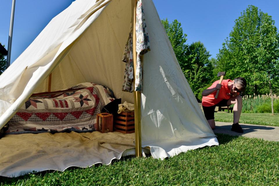 Julie Rossington drives in a stake to secure her frontier dwelling Friday morning at Lowe-Volk Park. The display will be part of the Living History Days event, which runs through Sunday afternoon.