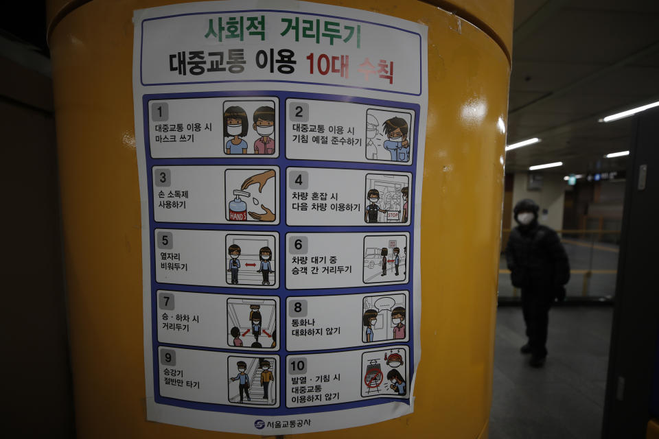 A man wearing a face mask walks near a banner displaying precautions against the coronavirus at a subway station in Seoul, South Korea, Sunday, Dec. 27, 2020. The banner reads: "Social distancing for public transportation." (AP Photo/Lee Jin-man)