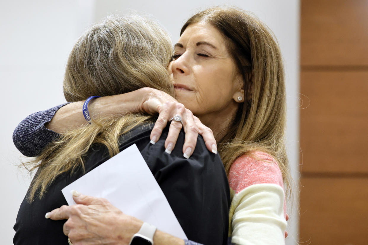 Linda Beigel Schulman, right, hugs Debbie Hixon tightly, her eyes closed.