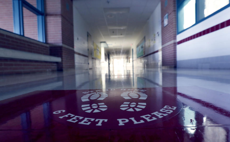 A social distancing reminder sits on the floor of an empty hallway at Stephens Elementary School in Rowlett, Texas, Wednesday, July 22, 2020.(AP Photo/LM Otero)