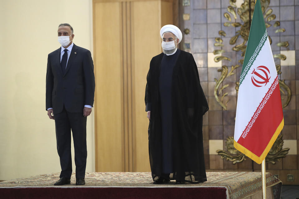 In this photo released by the official website of the office of the Iranian Presidency, President Hassan Rouhani, right, welcomes Iraqi Prime Minister Mustafa al-Kadhimi as they wear protective face masks to help prevent spread of the coronavirus, during an official arrival ceremony, in Tehran, Iran, Tuesday, July 21, 2020. (Iranian Presidency Office via AP)