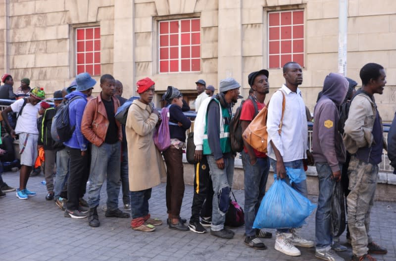 Homeless people stand in a queue before being transported to a homeless shelter during the first day of a nationwide lockdown for 21 days to try to contain the coronavirus disease (COVID-19) outbreak, in Johannesburg