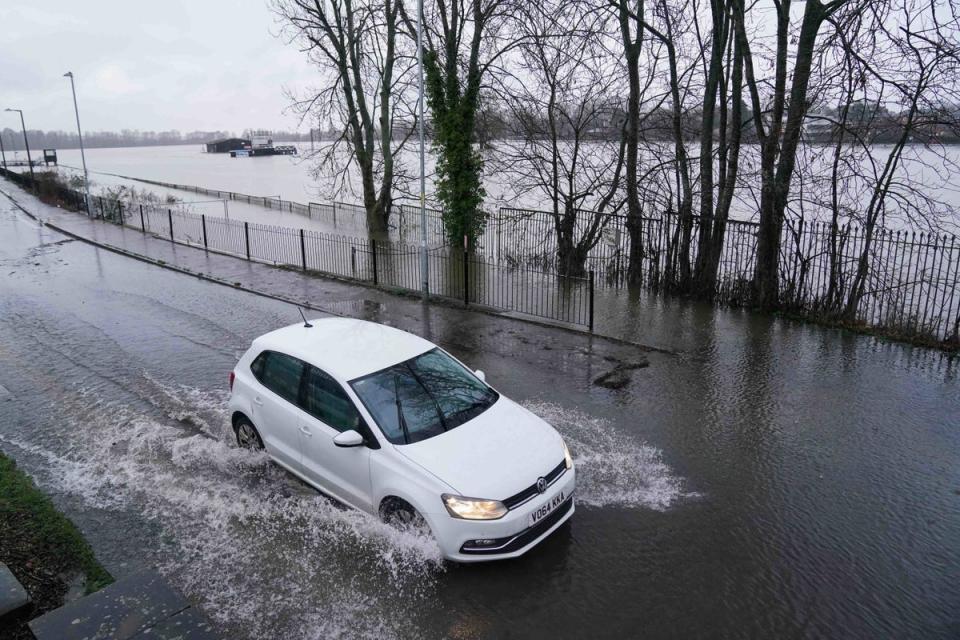 A vehicle drives through standing water close to a flooded Worcester racecourse (PA)