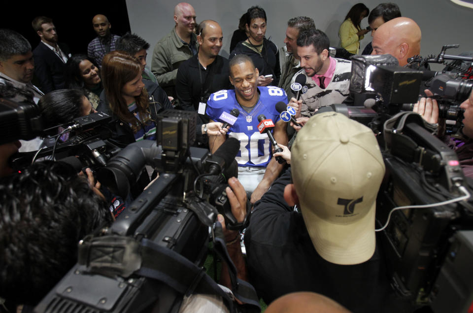 New York Giants' Victor Cruz smiles while surrounded by reporters during a presentation in New York, Tuesday, April 3, 2012. The NFL and Nike showed off the new gear in grand style with a gridiron-themed fashion show at a Brooklyn film studio. (AP Photo/Seth Wenig)