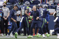 Seattle Seahawks head coach Pete Carroll, center, and his son, wide receivers coach Nate Carroll, left, greet wide receiver Freddie Swain after Swain scored a touchdown against the Tennessee Titans during the second half of an NFL football game, Sunday, Sept. 19, 2021, in Seattle. (AP Photo/John Froschauer)