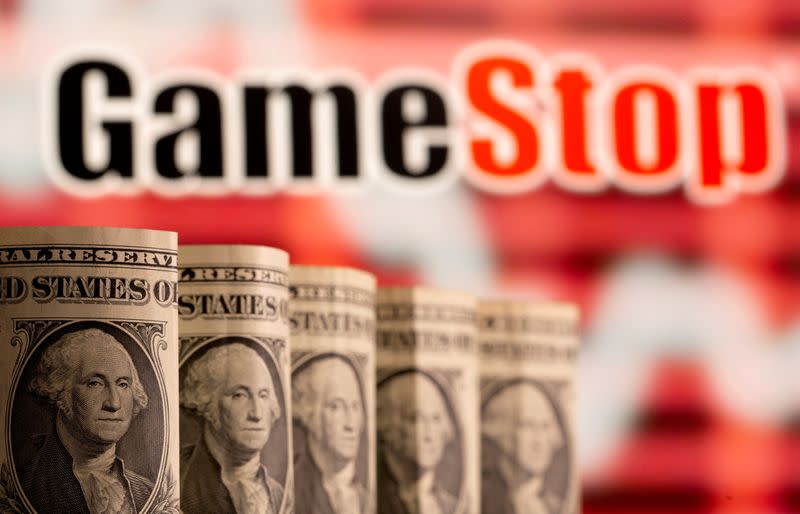FILE PHOTO: U.S. one dollar banknotes are seen in front of displayed GameStop logo