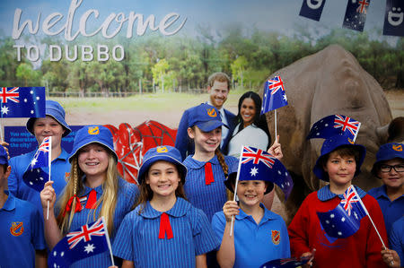 Children from Dubbo Public School wave Australia's national flags while waiting for Britain's Prince Harry and his wife Meghan, Duchess of Sussex, to arrive at Dubbo airport, Dubbo, Australia October 17, 2018. REUTERS/Phil Noble