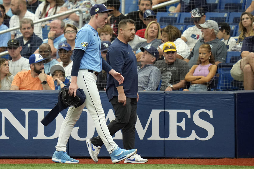 Tampa Bay Rays relief pitcher Pete Fairbanks leaves the field with a trainer after getting injured while warming up during the ninth inning of a baseball game against the Los Angeles Dodgers Sunday, May 28, 2023, in St. Petersburg, Fla. (AP Photo/Chris O'Meara)