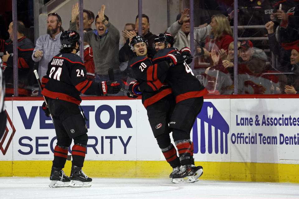 Carolina Hurricanes' Jordan Martinook, right, is congratulate by Sebastian Aho (20) with Seth Jarvis (24) nearby during the first period of an NHL hockey game against the Calgary Flames in Raleigh, N.C., Sunday, March 10, 2024. (AP Photo/Karl B DeBlaker)