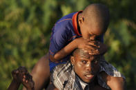 A man carries a boy over the Rio Grande river as migrants, many from Haiti, leave Del Rio, Texas to return to Ciudad Acuna, Mexico, early Wednesday, Sept. 22, 2021, some to avoid possible deportation from the U.S. and others to load up on supplies. (AP Photo/Fernando Llano)