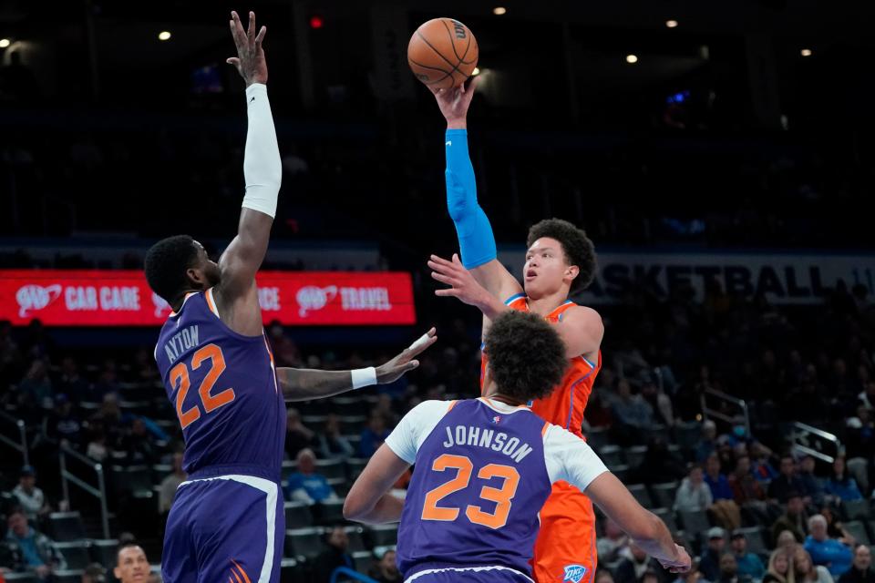 Oklahoma City Thunder forward Isaiah Roby, right, shoots in front of Phoenix Suns center Deandre Ayton (22) and forward Cameron Johnson (23) in the first half of an NBA basketball game Thursday, Feb. 24, 2022, in Oklahoma City. (AP Photo/Sue Ogrocki)