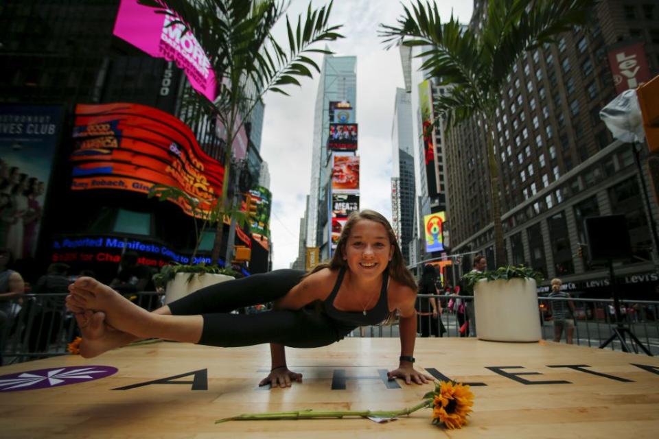 A young participant makes a pose during an event where people practice yoga in Times Square as part of a Summer Solstice celebration on International Yoga Day in New York June 21, 2015. REUTERS/Eduardo Munoz - RTX1HHF3