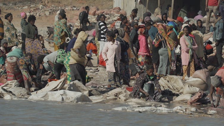 A large group of 'washers' clean ore are a washing pit.