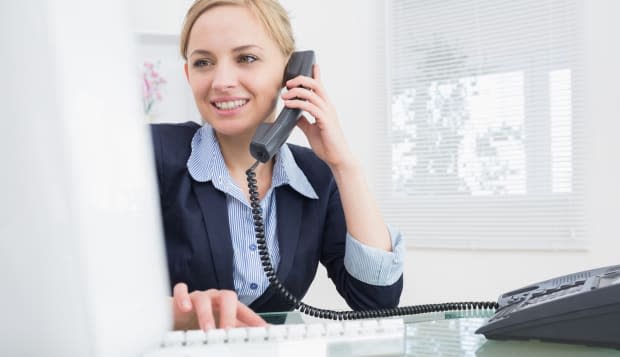 Female executive using phone and computer at office