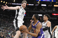 Phoenix Suns' Mikal Bridges, center, looks to pass the ballas he is defended by San Antonio Spurs' Jakob Poeltl (25) and Tre Jones during the second half of an NBA basketball game, Saturday, Jan. 28, 2023, in San Antonio. (AP Photo/Darren Abate)