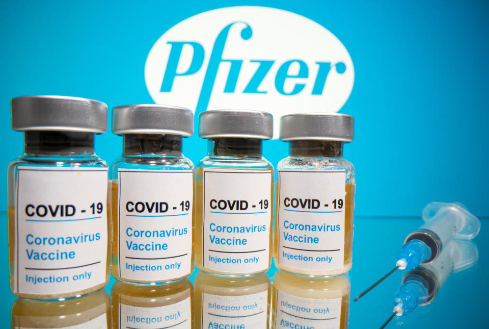 Vials with a sticker reading, "COVID-19 / Coronavirus vaccine / Injection only" and a medical syringe are seen in front of a displayed Pfizer logo in this illustration taken October 31, 2020. REUTERS/Dado Ruvic/Illustration
