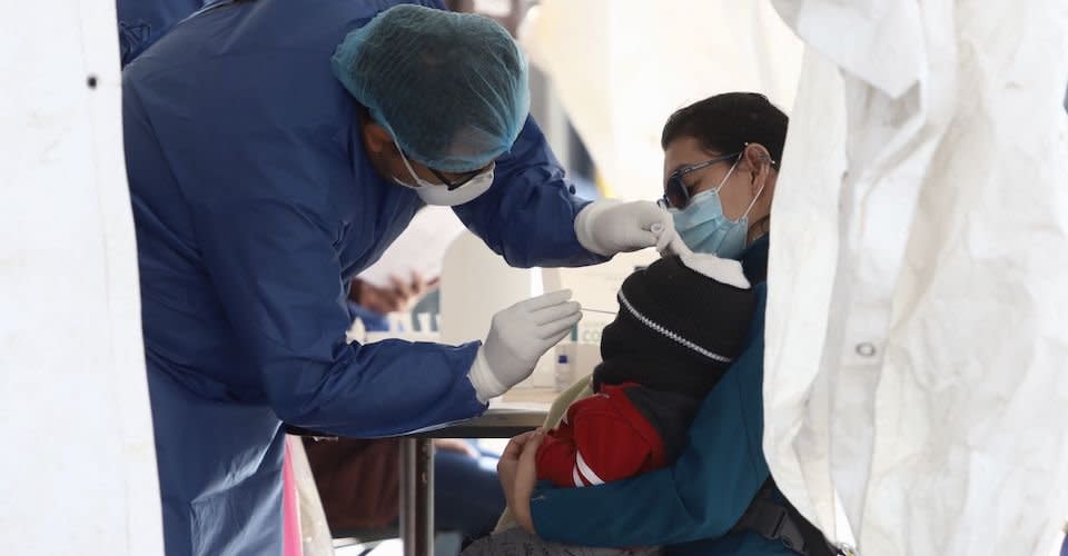 Personal de salud le practica una prueba de Covid-19 a un niño en el regazo de su mamá en el Kiosco instalado en la explanada de la Alcaldía Gustavo A. Madero, puesto que se contabilizan aumentos de casos de la variante ómicron en la población de la capital.