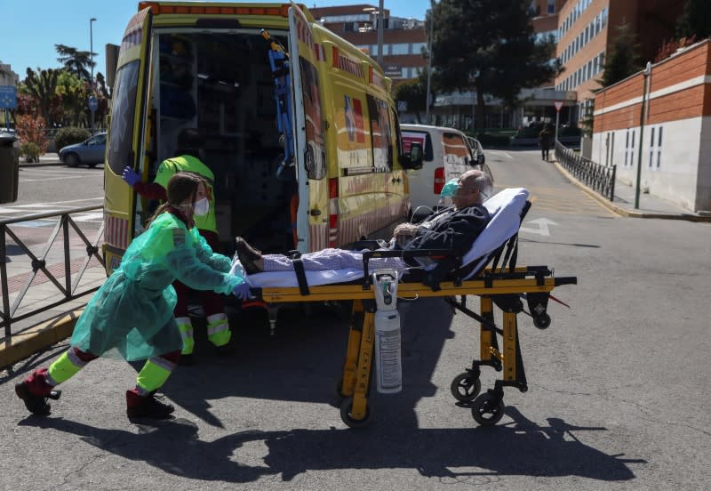 FOTO DE ARCHIVO: Un trabajador de la salud con una mascarilla y traje de protección transporta a un paciente en Madrid