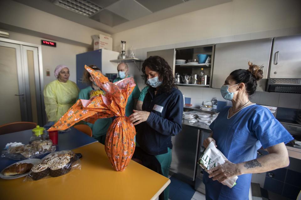 In this photo taken on Friday, April 10, 2020, nurse Cristina Settembrese, right, shares food and Easter eggs with colleagues at the San Paolo hospital before starting her work shift in Milan, Italy. (AP Photo/Luca Bruno)