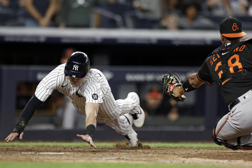 New York Yankees' Tyler Wade, left, scores a run behind Baltimore Orioles catcher Pedro Severino during the 10th inning of a baseball game on Friday, Sept. 3, 2021, in New York. (AP Photo/Adam Hunger)