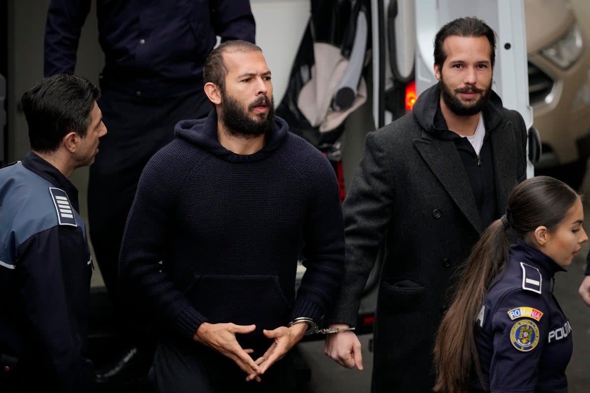 Officers escort Andrew Tate, centre, and his brother Tristan Tate to the Court of Appeal in Bucharest (AP)