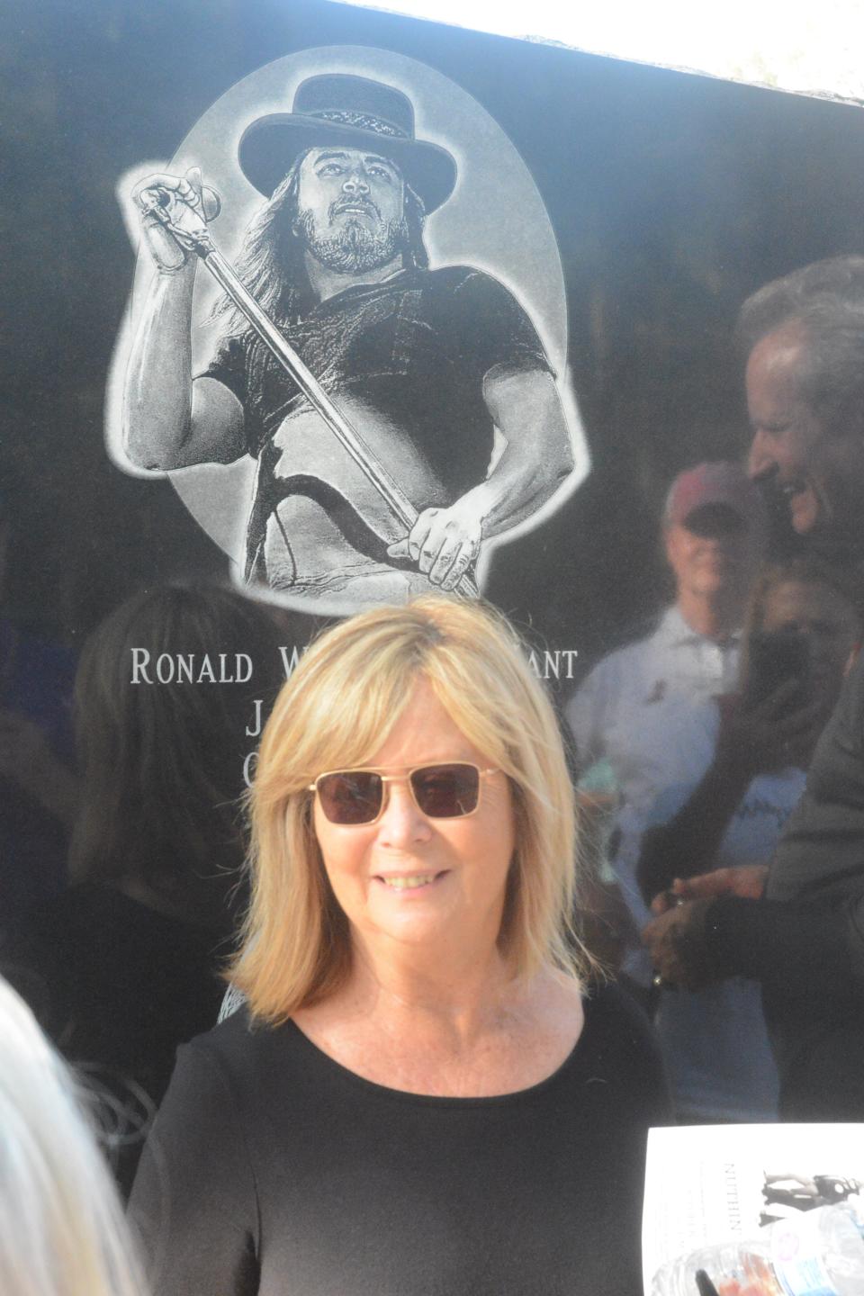 Judy Van Zant-Jenness stands below a sketch of the late Ronnie Van Zant, the original lead singer of the Southern rock band, Lynyrd Skynyrd. The sketch is part of a monument to the band members who lost their lives following a plane crash near Gillsburg, Miss., on Oct. 20, 1977. Van Zant-Jenness, his widow, helped unveil the monument at a ceremony on Oct. 20, 2019.