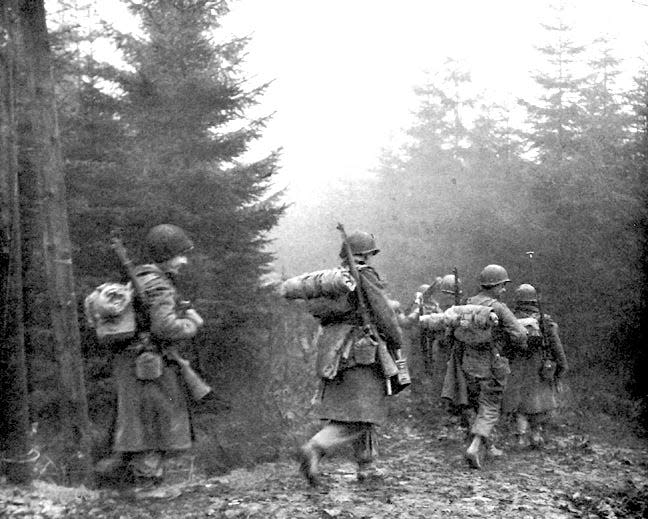 Men of the 325th Glider Infantry Regiment move through fog to a new position near Bastogne, Belgium, in December 1944.