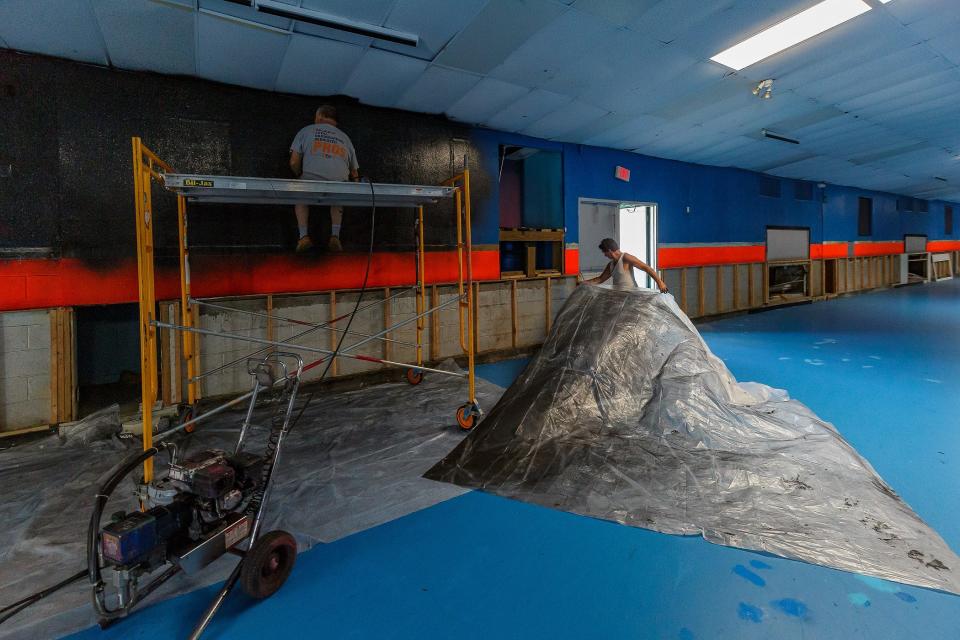 Jim Joline, left and Rex Smith apply new black pain to the walls at the newest Astro Skate location in Greenacres, Fla., on March 2, 2023.