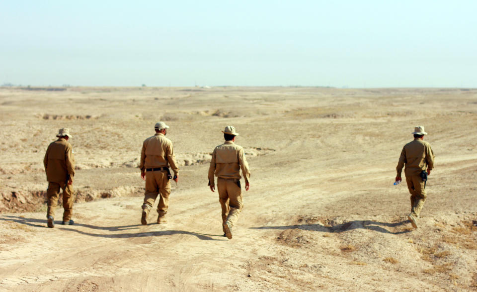 The FSD's Team 1 walks out among the trenches behind the frontlines, where Peshmerga have set up fortified hills, to prepare for a detonation that will destroy explosives left behind by ISIS. (Photo: Ash Gallagher for Yahoo News)