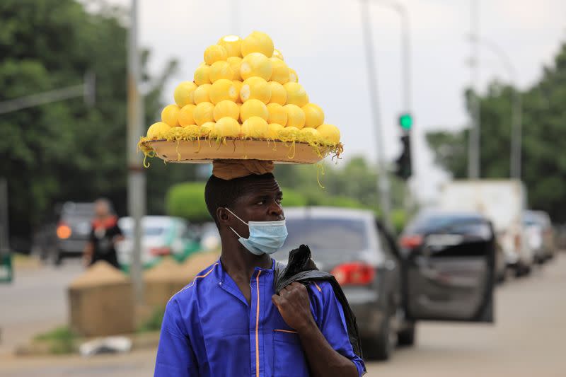 Man wears a protective face mask as he sells oranges on a street in Abuja