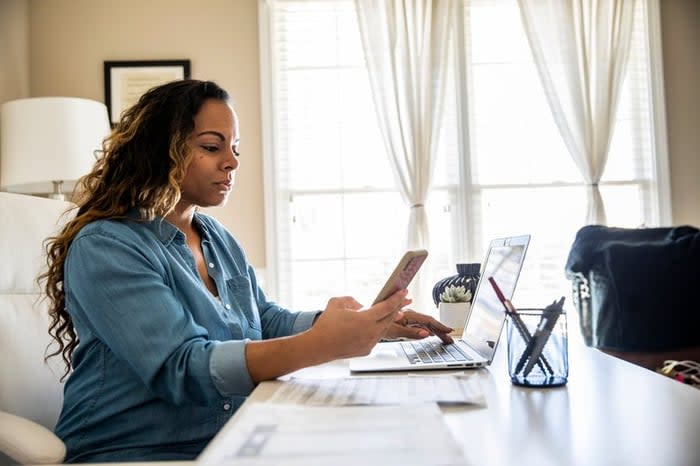 Woman using laptop and smartphone at home