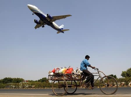 An IndiGo Airlines aircraft prepares to land as a man paddles his cycle rickshaw in Ahmedabad, October 26, 2015. REUTERS/Amit Dave/Files