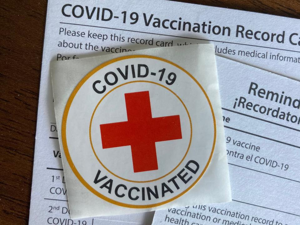 Vaccination cards and a sticker from the COVID-19 vaccine.