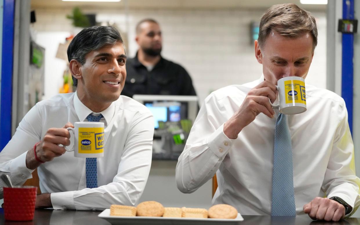 Sunak and Jeremy Hunt having a drink with biscuits during a visit to a builders warehouse in London