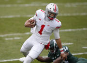 Ohio State quarterback Justin Fields (1) escapes from Michigan State linebacker Antjuan Simmons during the first half of an NCAA college football game, Saturday, Dec. 5, 2020, in East Lansing, Mich. (AP Photo/Al Goldis)