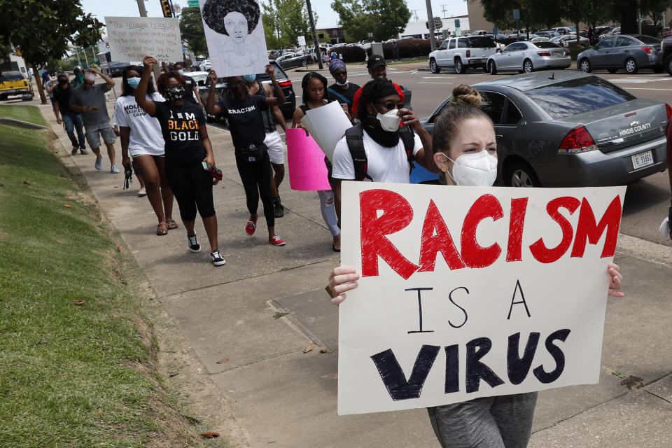 Angela Truex, of Jackson, Miss., carries a sign describing racism as a virus, during a march through downtown Jackson, Miss., Monday, June 1, 2020. (AP Photo/Rogelio V. Solis)