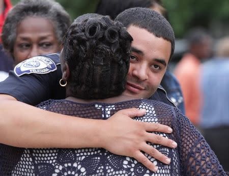 A police officer is embraced after a vigil for the fatal attack on Baton Rouge policemen, at Saint John the Baptist Church in Zachary, Louisiana, July 17, 2016. REUTERS/Jeffrey Dubinsky