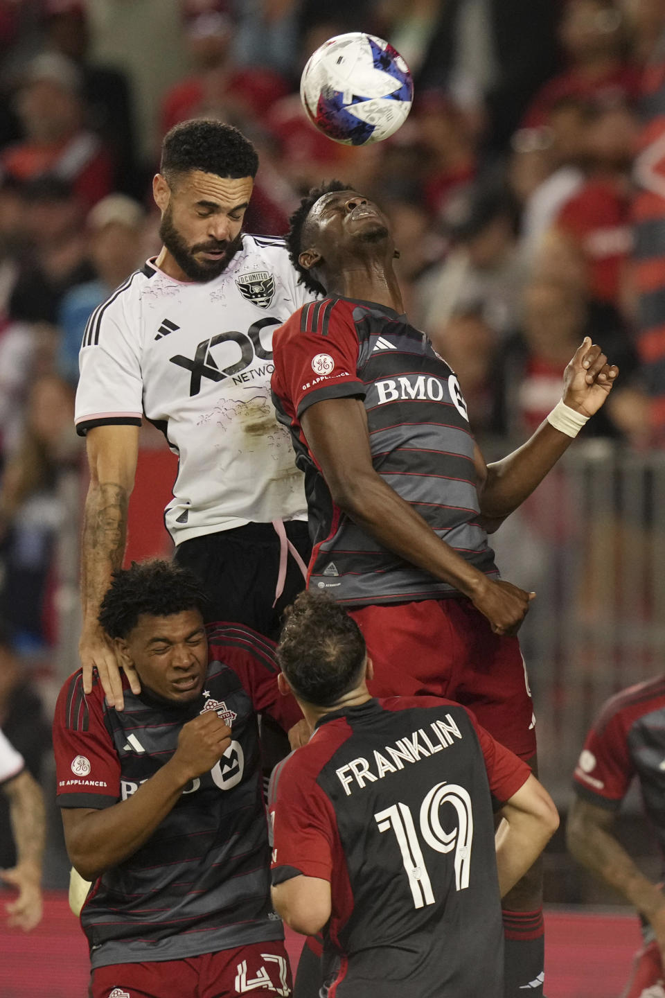 D.C. United defender Donovan Pines, top left, climbs above Toronto FC's Kosi Thompson, bottom left, to challenge Toronto FC's Aime Mabika, top right, for the ball during second-half MLS soccer match action in Toronto, Ontario, Saturday, May 27, 2023. (Chris Young/The Canadian Press via AP)