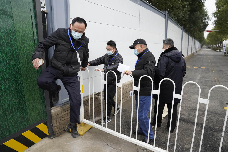 Security personnel jump across a barrier at an entrance to the Wuhan Jinyintan Hospital where a team from the World Health Organization visited in Wuhan in central China's Hubei province on Saturday, Jan. 30, 2021. (AP Photo/Ng Han Guan)