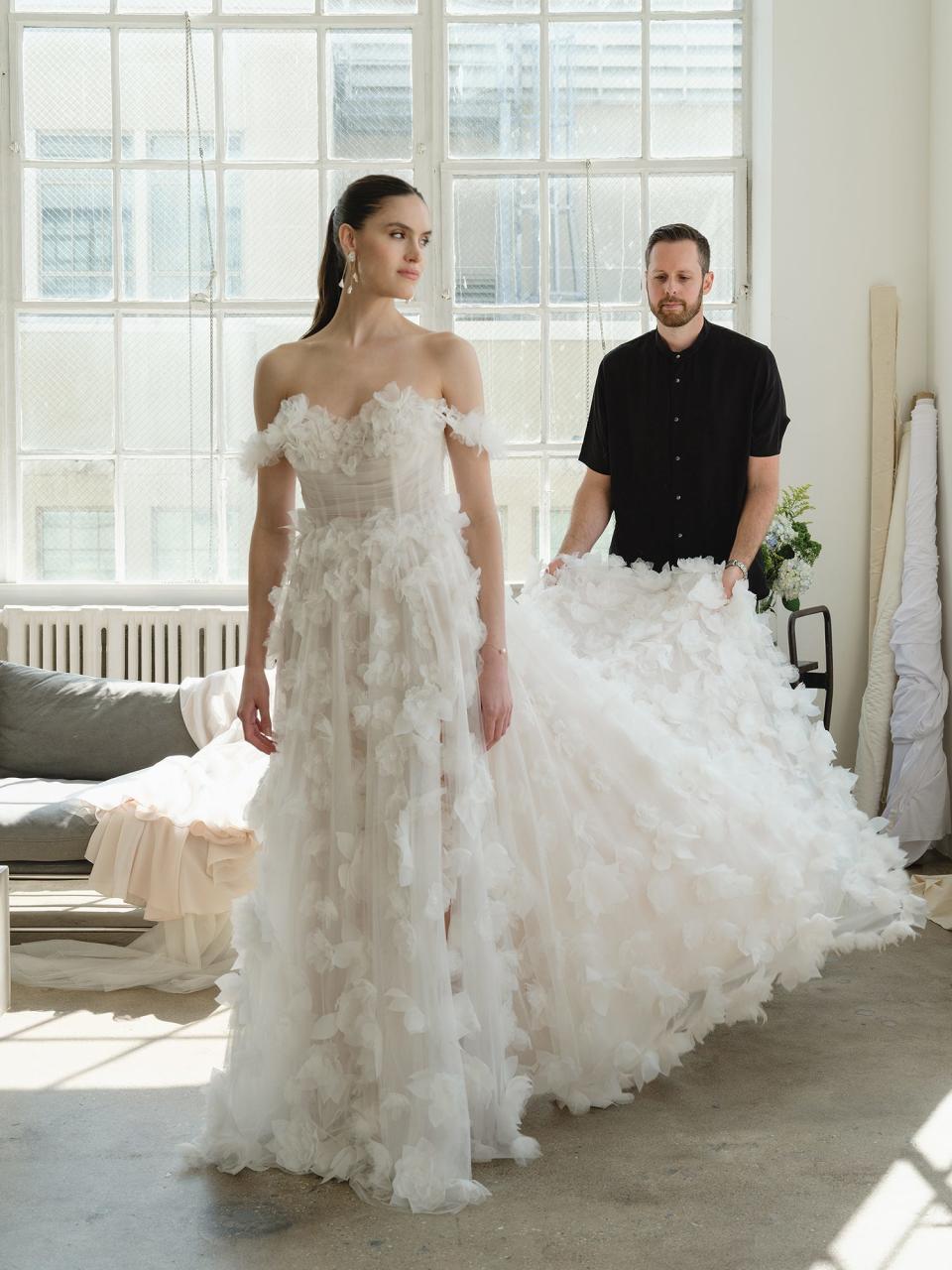 A man holds up the train of a bride's wedding dress.