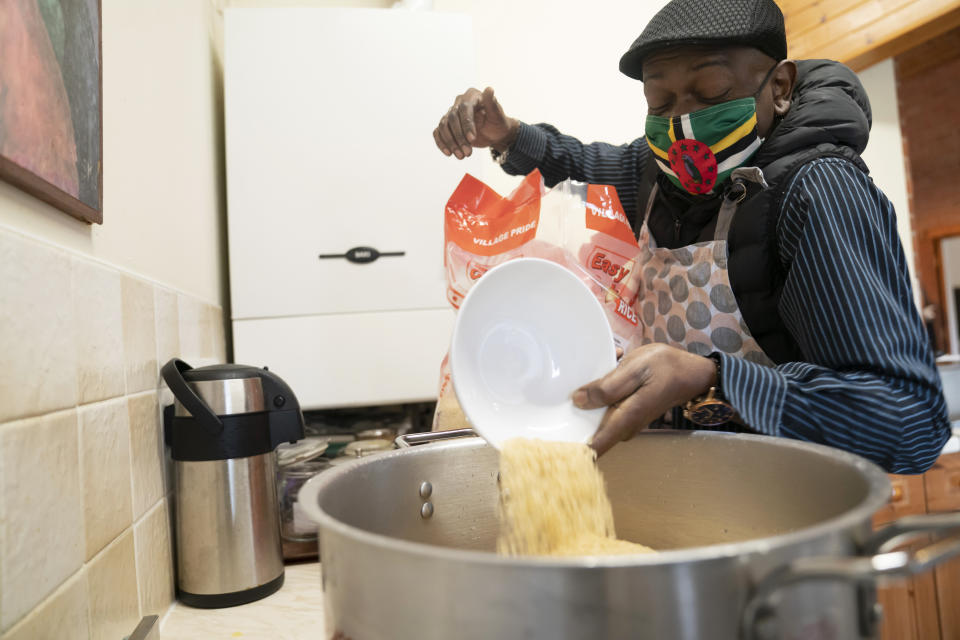 Volunteer Dave Williams pours in rice to cook as members of the Preston Windrush Covid Response team prepare West Indian meals, at the Xaverian Sanctuary, in Preston, England, Friday Feb. 19, 2021. Once a week, chief coordinator Glenda Andrew and her team distribute meals to people in Preston and surrounding communities in northwestern England that have recorded some of the U.K.’s highest coronavirus infection rates. The meal program grew out of Andrew’s work with Preston Windrush Generation & Descendants, a group organized to fight for the rights of early immigrants from the Caribbean and other former British colonies who found themselves threatened with deportation in recent years. (AP Photo/Jon Super)