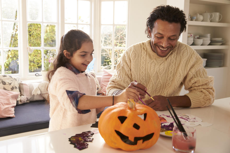 Father And Daughter Making Halloween Decorations At Home