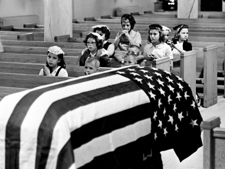 Mourners pray at the Holy Name Catholic Church over an empty casket drapes with the flag in respect to President John F. Kennedy after his death in Dallas on Nov. 22, 1963.