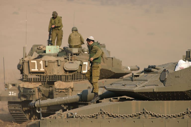 Soldados israelíes se encuentran en la parte superior de tanques Merkava posicionados en la Alta Galilea, en el norte de Israel, cerca de la frontera con Líbano, el 11 de octubre de 2023.