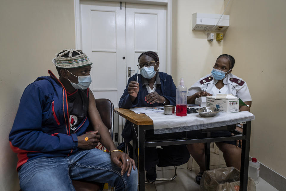 Medical staff talk to a man about to be vaccinated against COVID-19 at the Hillbrow Clinic in Johannesburg, South Africa, Monday Dec. 6, 2021. The new omicron variant appears to be driving a dramatic surge in South Africa, providing the world a glimpse of where the pandemic might be headed. (AP Photo/Shiraaz Mohamed)