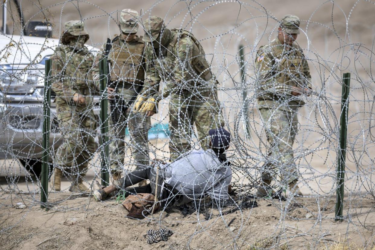 Texas National Guard troops try to untangle a migrant caught in razor wire along the Texas-Mexico border on Jan. 31, 2024. <a href="https://www.gettyimages.com/detail/news-photo/texas-national-guard-troops-try-to-untangle-an-immigrant-news-photo/1976393392?adppopup=true" rel="nofollow noopener" target="_blank" data-ylk="slk:John Moore/Getty Images;elm:context_link;itc:0;sec:content-canvas" class="link ">John Moore/Getty Images</a>