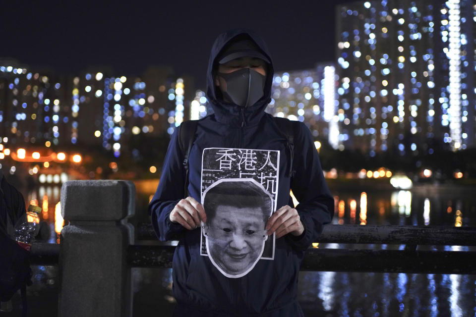 A protester holds a Chinese President Xi Jinping mask during a protest in Hong Kong, Friday, Oct. 18, 2019. Hong Kong pro-democracy protesters are donning cartoon/superhero masks as they formed a human chain across the semiautonomous Chinese city, in defiance of a government ban on face coverings. (AP Photo/Vincent You)