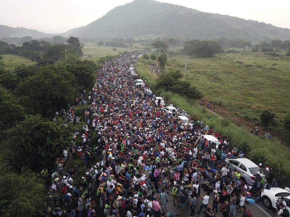 FILE - In this Oct. 27, 2018 file photo, members of a US-bound migrant caravan stand on a road after federal police briefly blocked their way outside the town of Arriaga, Mexico. Activists, officials and social workers in Central America were staggered by the idea that U.S. President Donald Trump thinks he will help reduce immigration by cutting off nearly $500 million in aid to Honduras, Guatemala and El Salvador; exactly the opposite will happen, they say. (AP Photo/Rodrigo Abd, File)