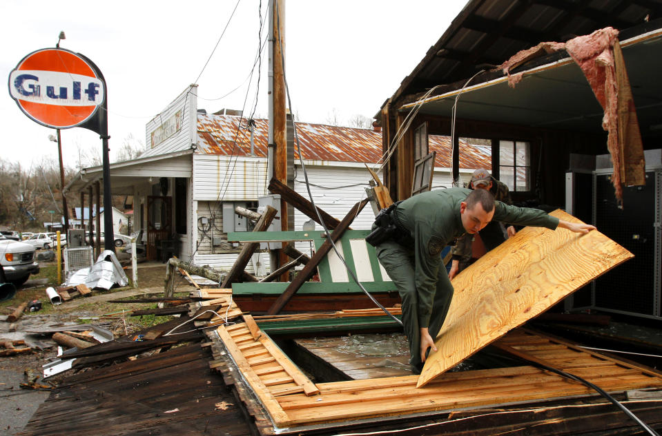 Hickman County Sheriff, Cody Woods helps remove debris from a house after a storm ripped through early morning on Wednesday, Jan. 30, 2013, in Coble, Tenn. A line of strong storms is pushing eastward across Tennessee, triggering tornado warnings and producing strong downpours of rain. (AP Photo/Butch Dill)